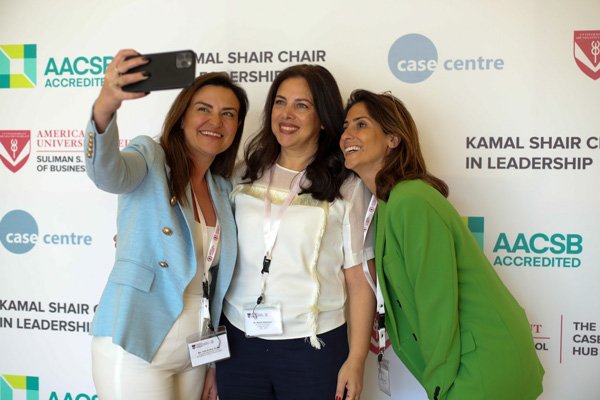 Three women in front of a Kamal Shair School of Leadership backdrop.