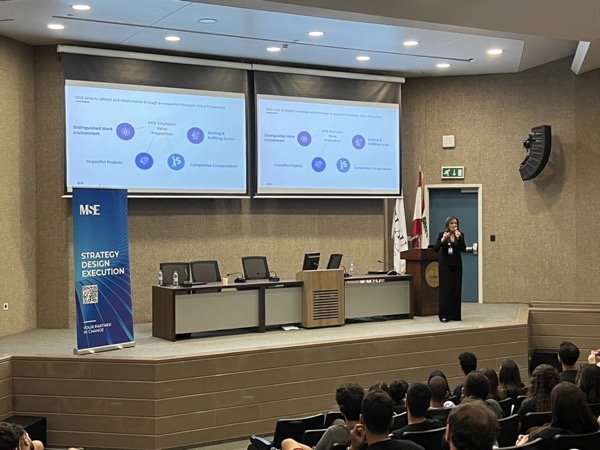 Hala Achkar Slaiby giving a presentation to a large conference audience.