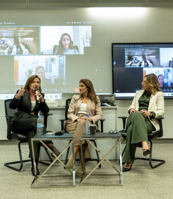 Three women seated in a panel discussion in a professional setting.