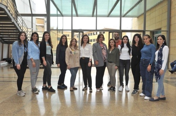 A group of twelve women in a bright, modern building.